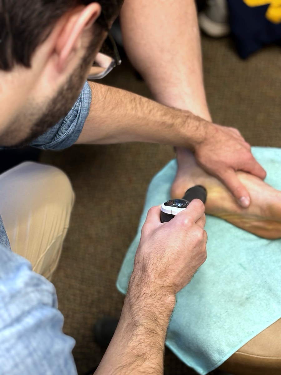 Dr. Coltin Golden applying shockwave therapy to the bottom of a patient's heel